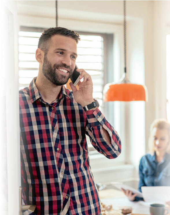 image of a man smiling in a plaid shirt talking on a smartphone